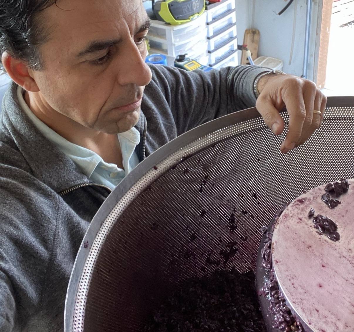 Guillermo Seta tending dark grape must at the press