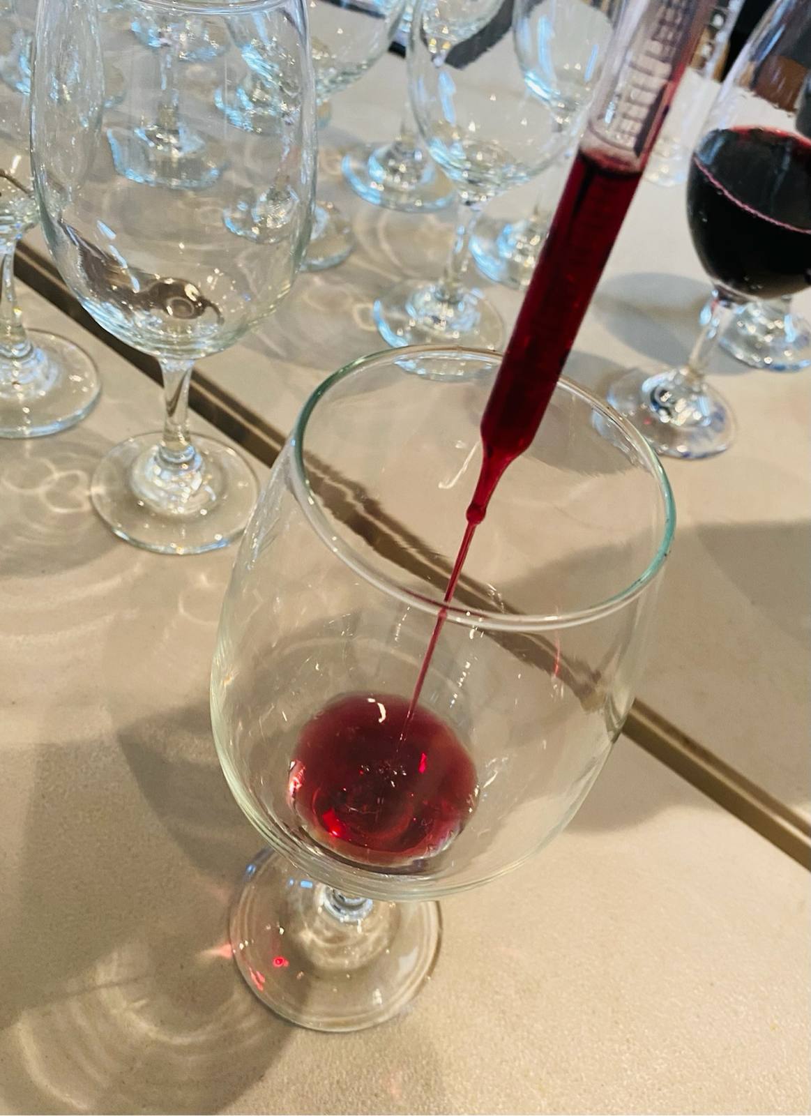 A wine pipette releasing a precise stream into a tasting glass