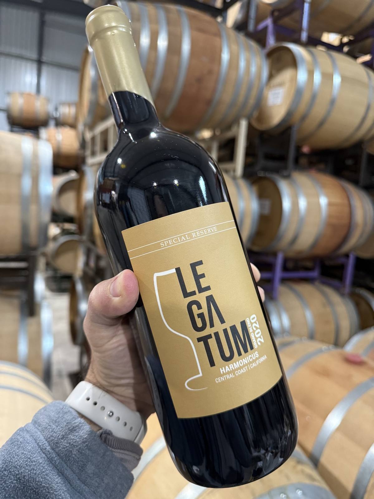 Legatum 2020 Harmonicus Special Reserve held among rows of oak barrels