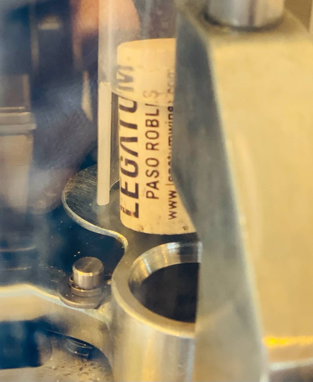 A corking machine driving a stamped Legatum Paso Robles cork into a bottle