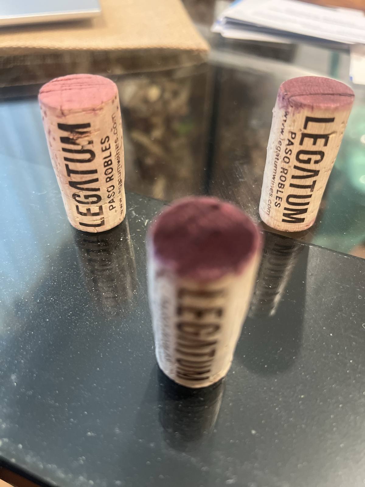 Wine-stained corks branded Legatum and Paso Robles standing on glass