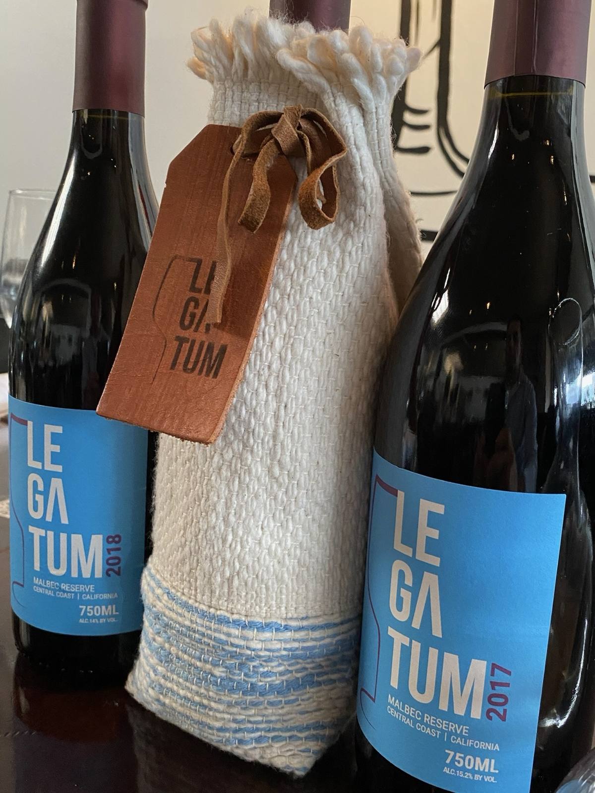 Hand-woven sleeve displayed between the Legatum 2017 and 2018 Malbec Reserve bottles
