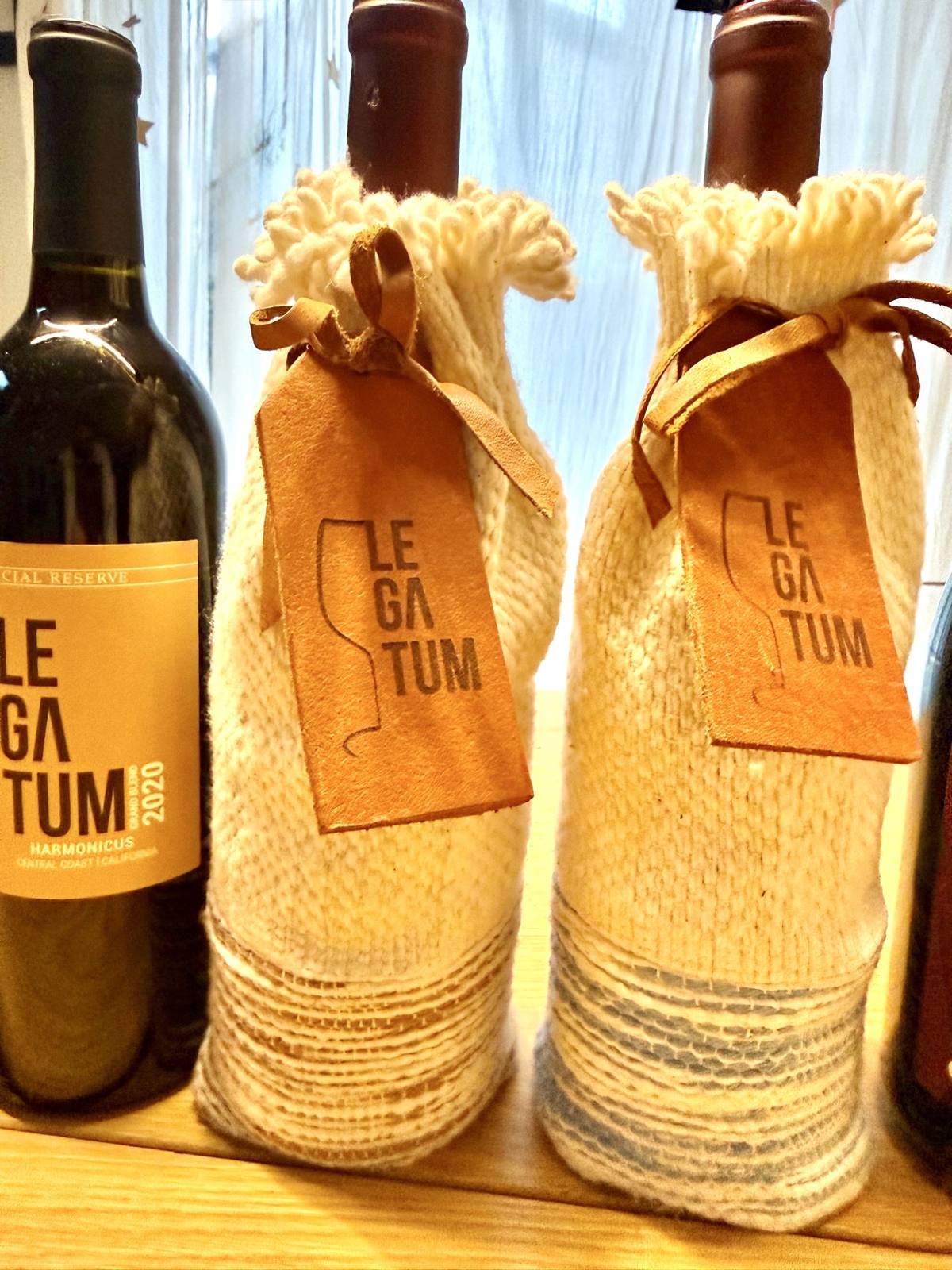 Two Legatum bottles in hand-woven sleeves with embossed leather tags beside the 2020 Harmonicus