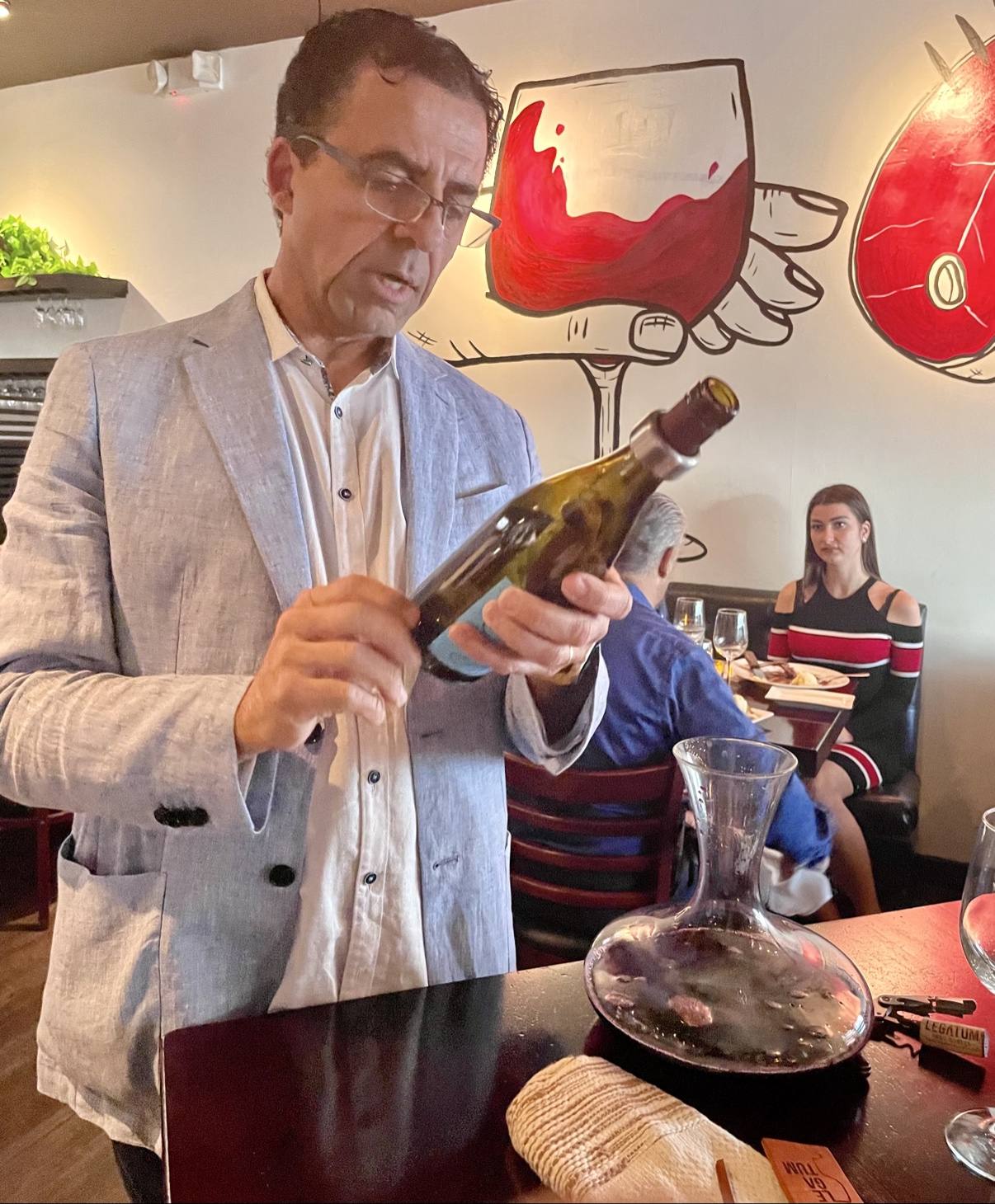 Guillermo Seta pouring Legatum into a glass decanter at the tasting table