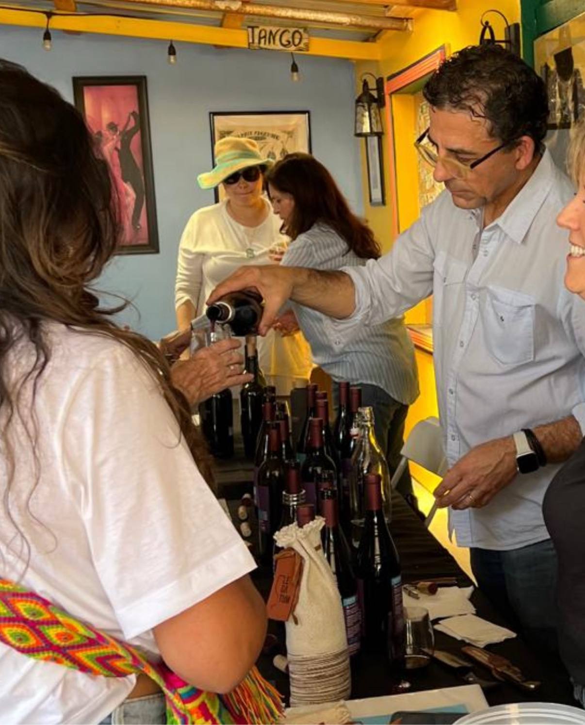 Guillermo Seta pouring Legatum beneath the illuminated TANGO sign at an Argentinian bar