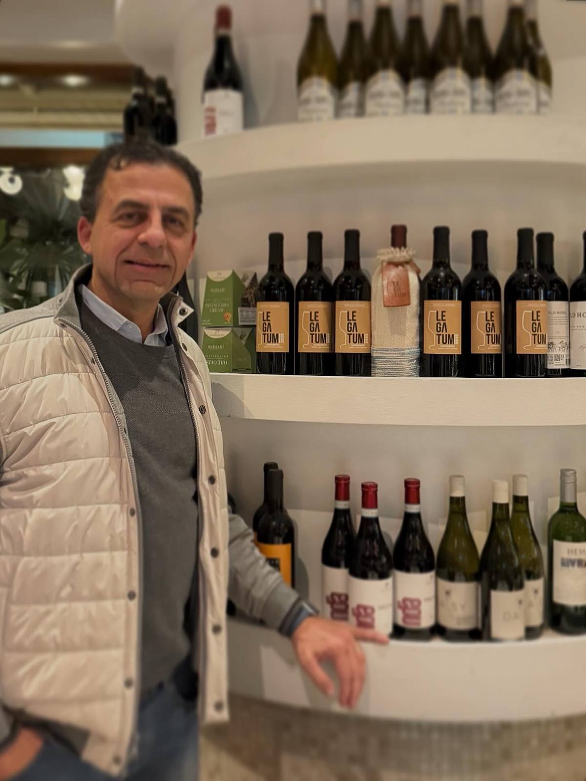 Guillermo Seta beside Toscanova’s curved shelf of Legatum bottles and a hand-woven sleeve