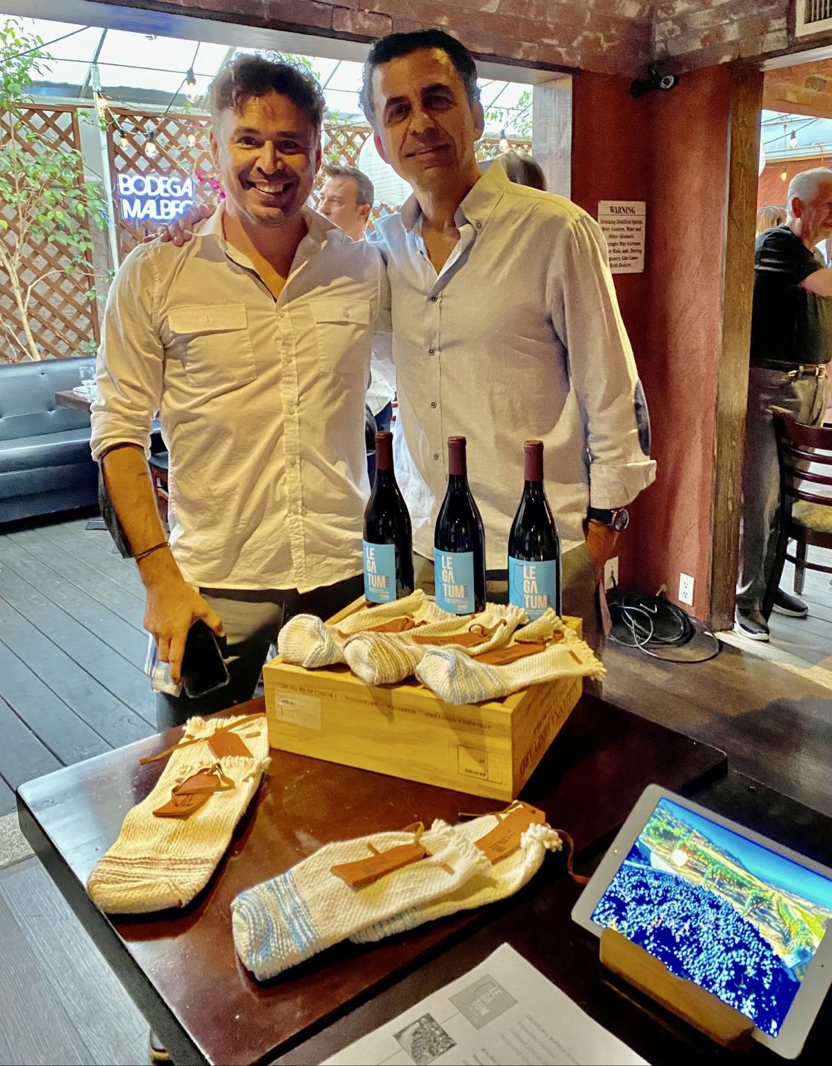 Guillermo Seta and a young colleague presenting Legatum beneath the Bodega Malbec neon sign