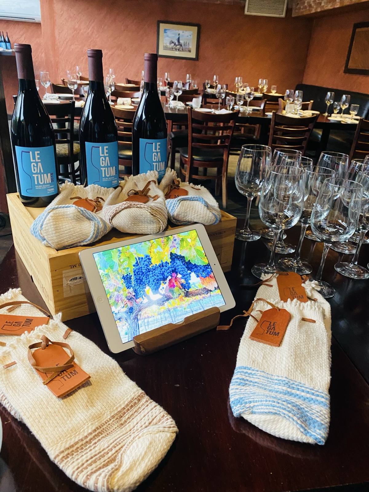 A tablet showing the Legatum vineyard beside bottles at Bodega Malbec