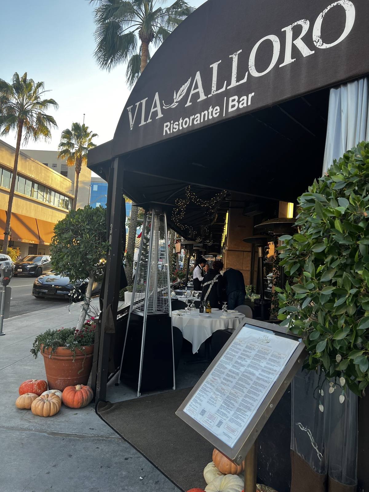 Via Alloro’s daytime entrance with autumn pumpkins beside the awning
