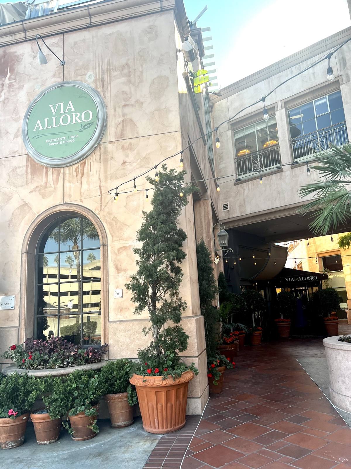 Via Alloro courtyard entrance with string lights and terracotta planters